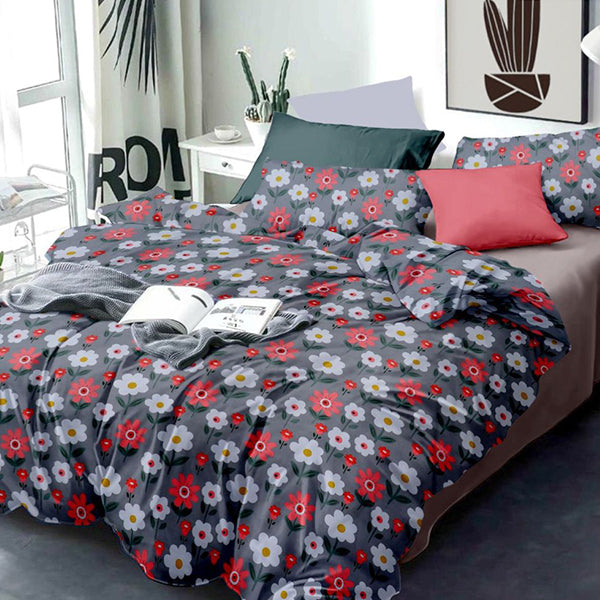 Floral patterned bedspread on a bed with a red pillow in a bedroom setting.