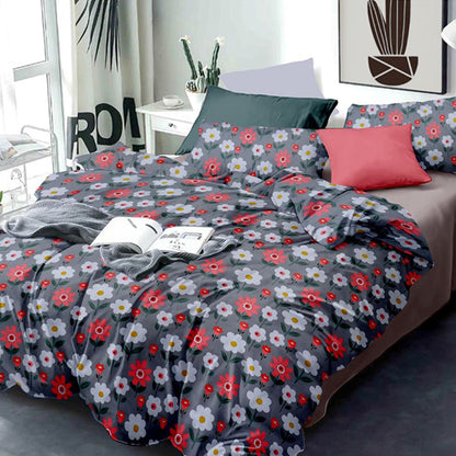Floral patterned bedspread on a bed with a red pillow in a bedroom setting.