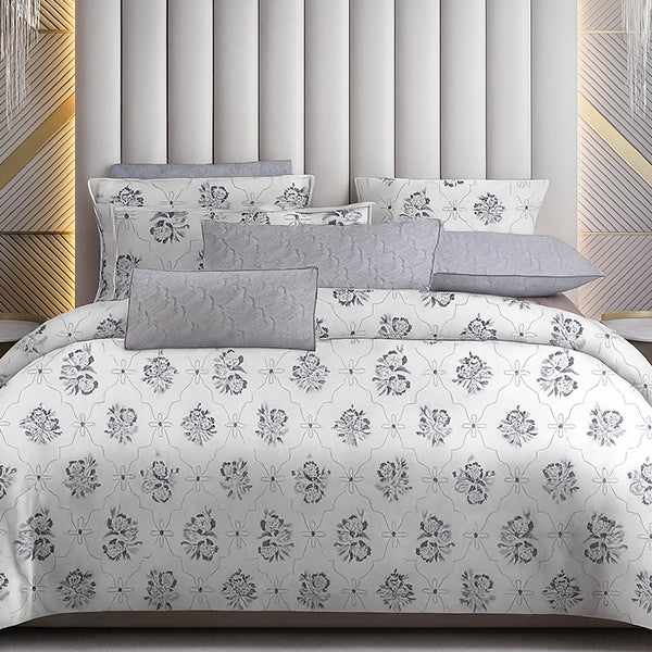 Bedding set with floral pattern on a bed against a geometric headboard.