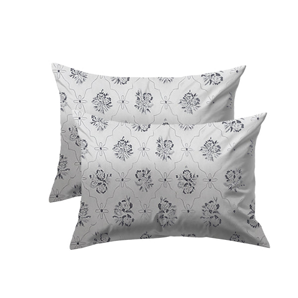 Two floral-patterned pillows on a white background wih bedsheet