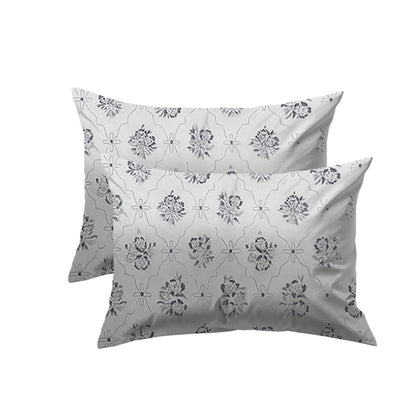 Two floral-patterned pillows on a white background wih bedsheet