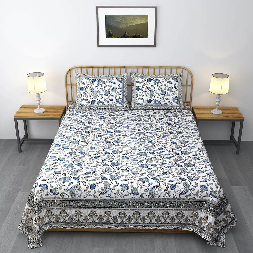 Bed with floral patterned bedding in a bedroom setting Blue Floral Peacock White Base Jaipuri Gold Print Bedsheet