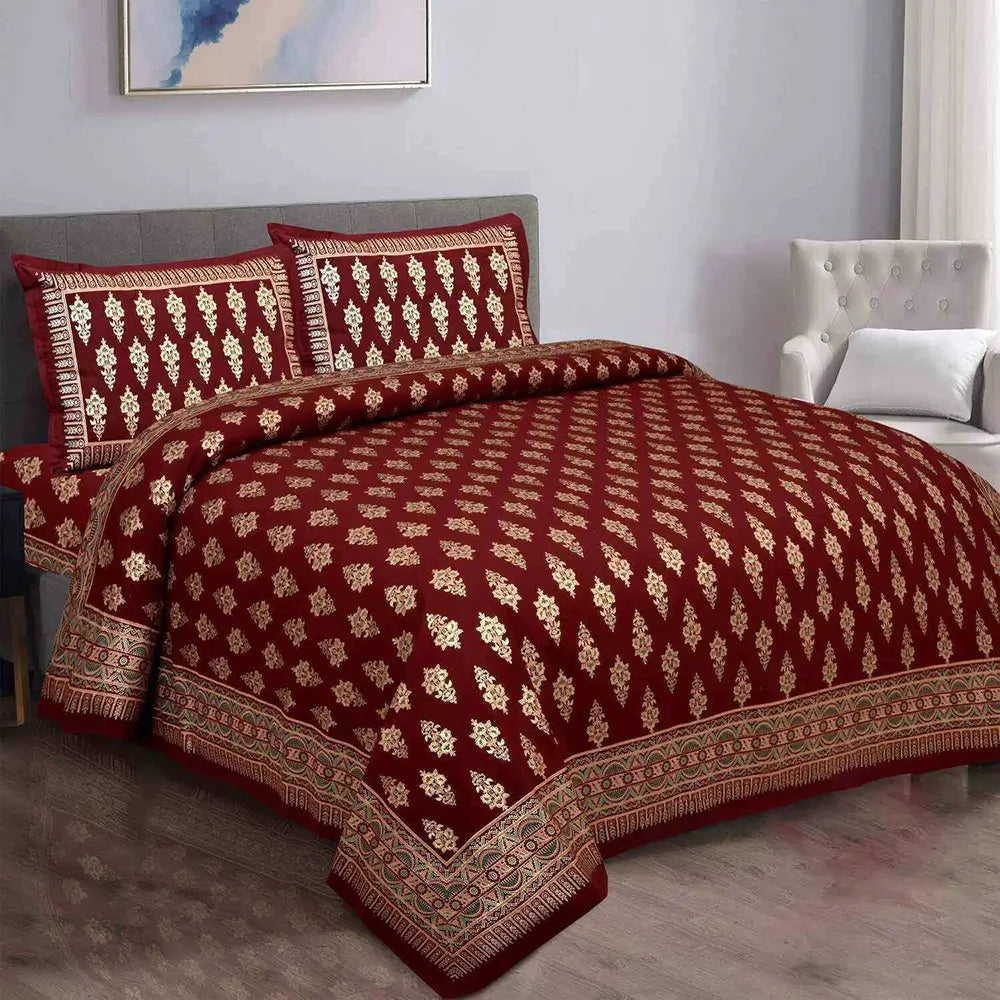 Red and gold patterned bedspread on a bed in a bedroom setting.