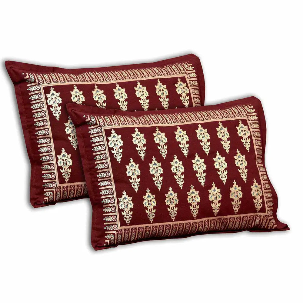 Two red pillows with gold patterns on a white background with bedsheet