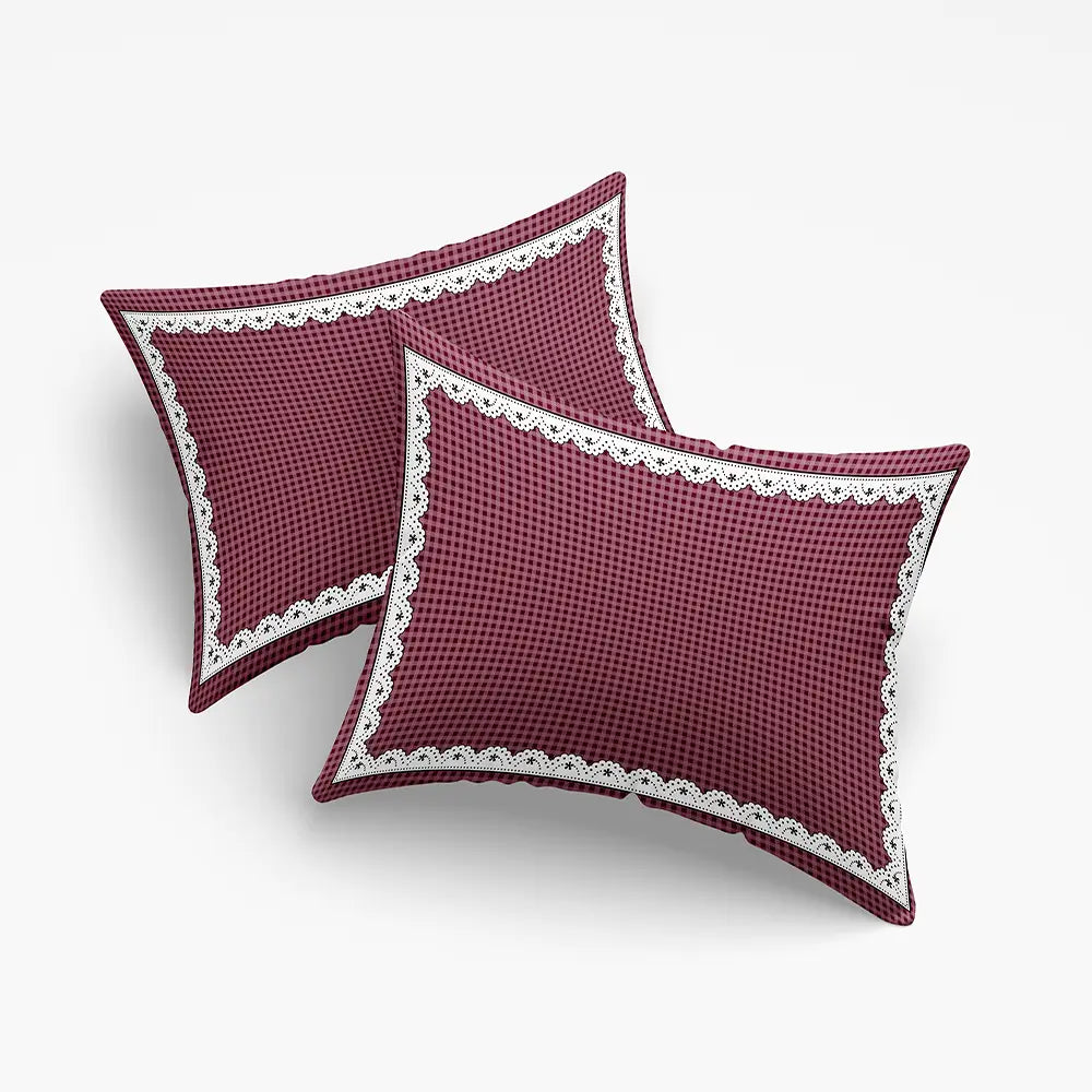 Two maroon pillows with white lace trim on a light gray background