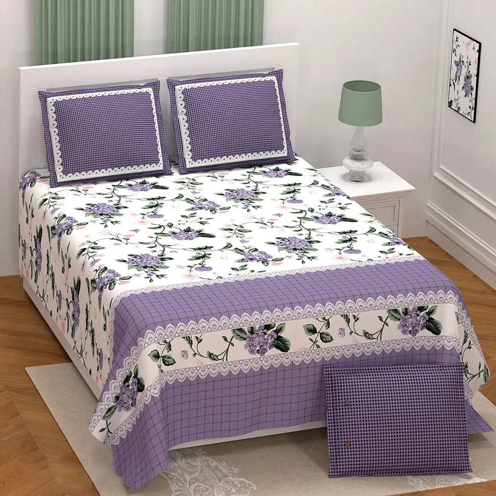 Floral bedspread set with purple accents on a bed in a bedroom.