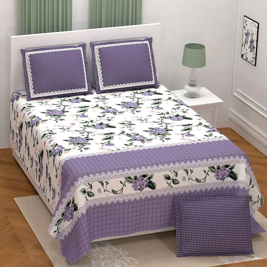 Floral bedspread set with purple accents on a bed in a bedroom.